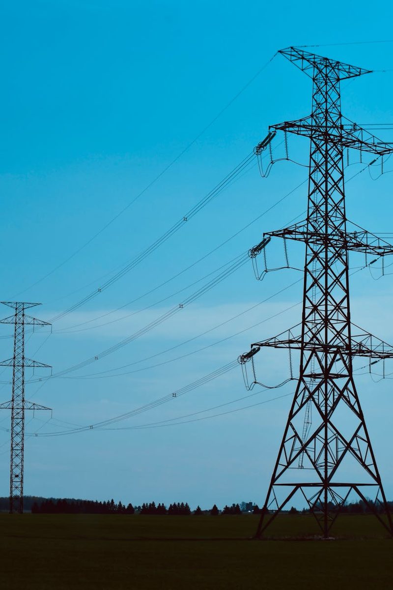 Tall electrical transmission towers against a blue sky, symbolizing energy and power distribution.